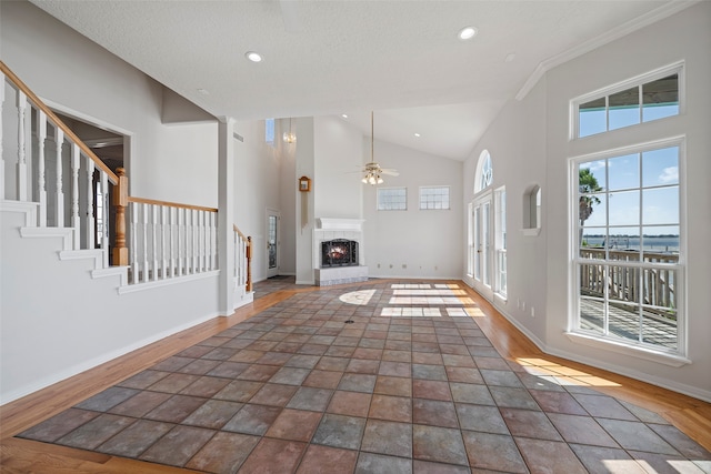 unfurnished living room with a textured ceiling, ceiling fan, crown molding, high vaulted ceiling, and dark hardwood / wood-style floors