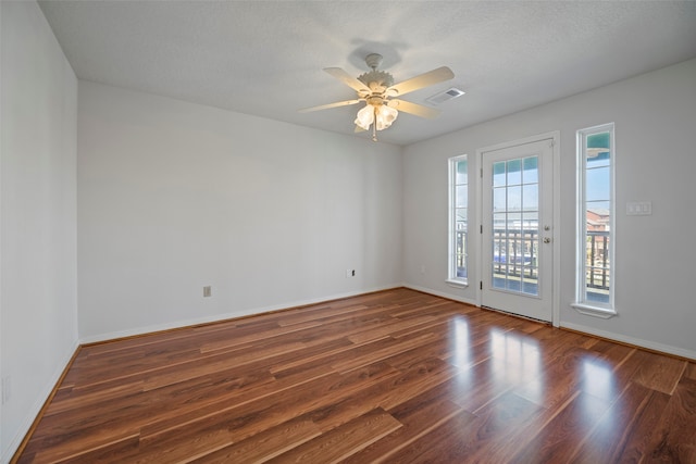 empty room with dark wood-type flooring, a textured ceiling, and ceiling fan