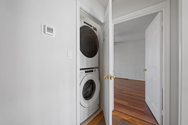 laundry area with dark hardwood / wood-style floors and stacked washer and clothes dryer