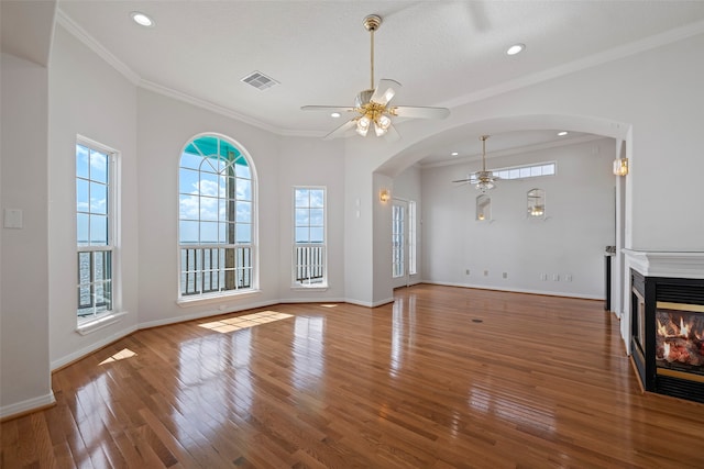 unfurnished living room featuring a multi sided fireplace, hardwood / wood-style floors, crown molding, a textured ceiling, and ceiling fan