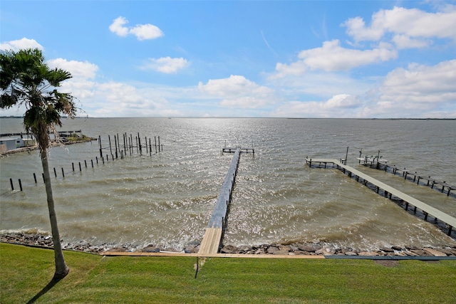 view of dock with a water view and a lawn