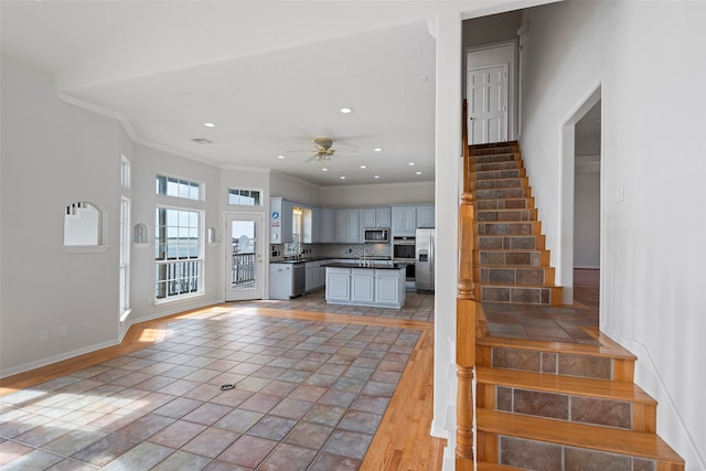 interior space with decorative backsplash, stainless steel appliances, crown molding, light wood-type flooring, and ceiling fan