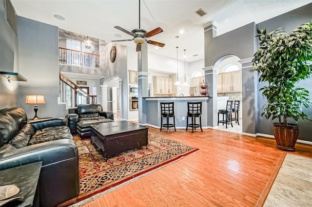 living room featuring ceiling fan, wood-type flooring, and a towering ceiling