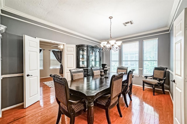 dining area featuring ceiling fan with notable chandelier, hardwood / wood-style floors, a textured ceiling, and ornamental molding