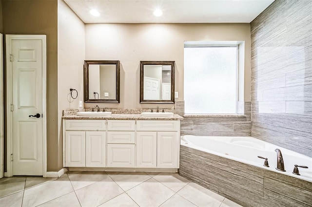 bathroom featuring tile patterned floors, vanity, and tiled bath