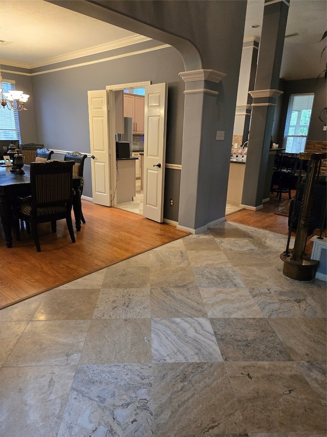 interior space with ornate columns, light hardwood / wood-style flooring, ornamental molding, and a notable chandelier