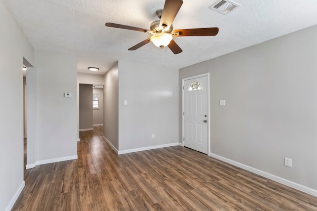 empty room featuring dark wood-type flooring, ceiling fan, and a textured ceiling