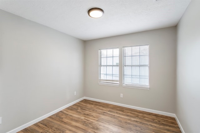 spare room with a textured ceiling and dark hardwood / wood-style flooring