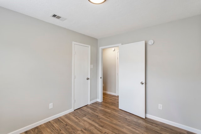 unfurnished bedroom with dark hardwood / wood-style flooring