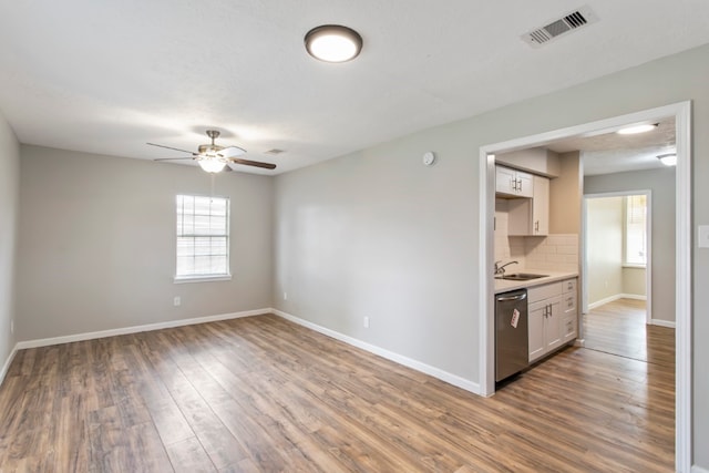 kitchen featuring dishwasher, wood-type flooring, sink, tasteful backsplash, and ceiling fan