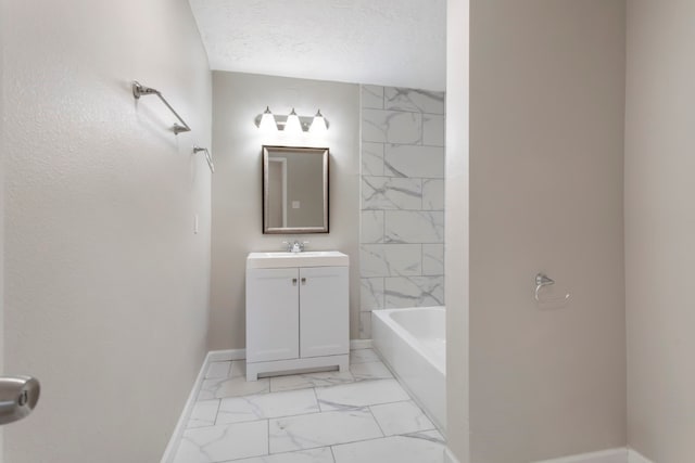 bathroom with vanity, a textured ceiling, and a bath