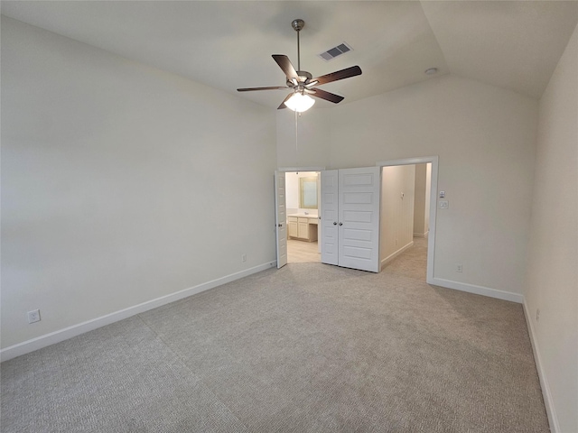 unfurnished bedroom with ceiling fan, light colored carpet, high vaulted ceiling, and ensuite bath