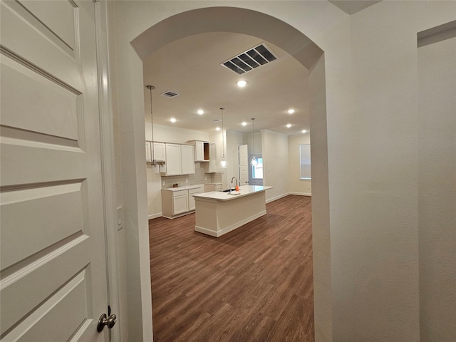 kitchen with a center island, backsplash, white cabinets, decorative light fixtures, and dark hardwood / wood-style flooring