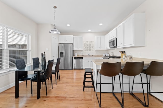 kitchen featuring white cabinetry, stainless steel appliances, sink, and light wood-type flooring