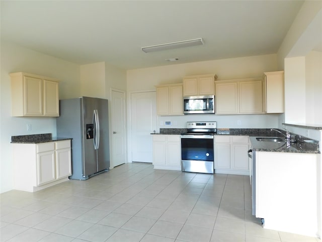 kitchen with sink, appliances with stainless steel finishes, dark stone counters, and light tile patterned floors