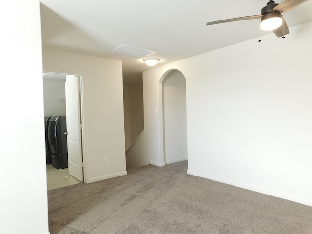 empty room with light carpet, washing machine and clothes dryer, and ceiling fan