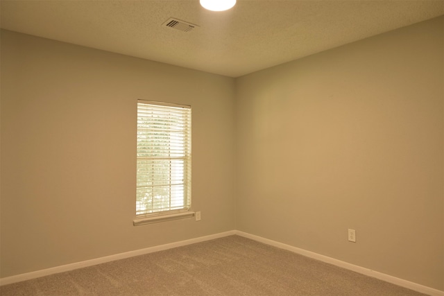 carpeted empty room featuring a textured ceiling