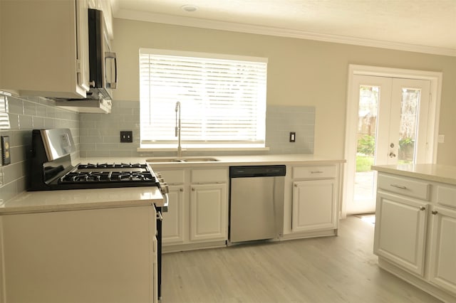 kitchen featuring appliances with stainless steel finishes, a healthy amount of sunlight, sink, and light wood-type flooring