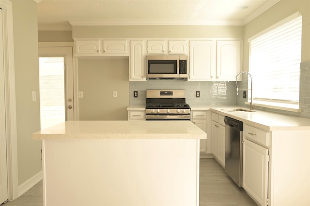 kitchen featuring a kitchen island, stainless steel appliances, sink, white cabinetry, and light hardwood / wood-style floors