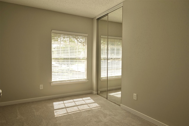 unfurnished room featuring carpet, a textured ceiling, and plenty of natural light