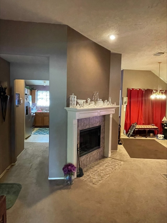 living room with lofted ceiling, a textured ceiling, a tiled fireplace, and carpet