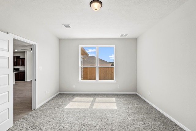 carpeted empty room featuring ceiling fan and a textured ceiling