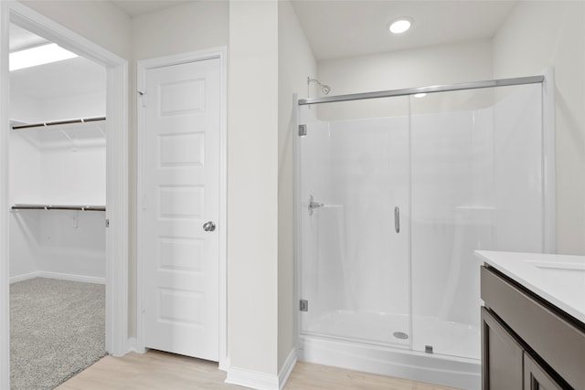 bathroom featuring hardwood / wood-style floors, vanity, and a shower with shower door