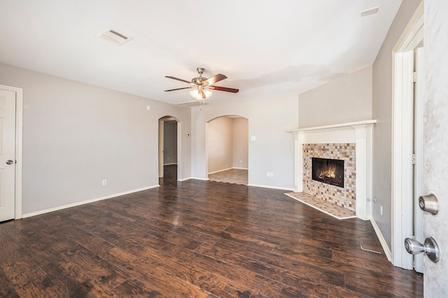 unfurnished living room with dark hardwood / wood-style floors, a tiled fireplace, and ceiling fan