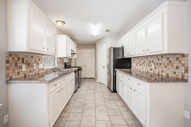 kitchen with tasteful backsplash, white cabinetry, dark stone counters, sink, and stainless steel appliances