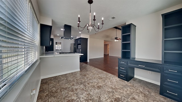 kitchen with kitchen peninsula, exhaust hood, hanging light fixtures, ceiling fan with notable chandelier, and blue cabinets