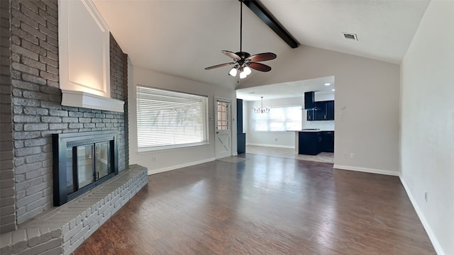 unfurnished living room featuring dark wood-type flooring, lofted ceiling with beams, a brick fireplace, and ceiling fan with notable chandelier