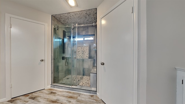 bathroom with a shower with door and wood-type flooring