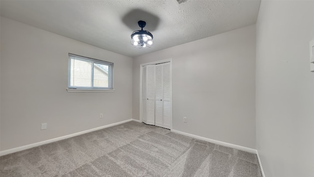 carpeted empty room featuring a textured ceiling