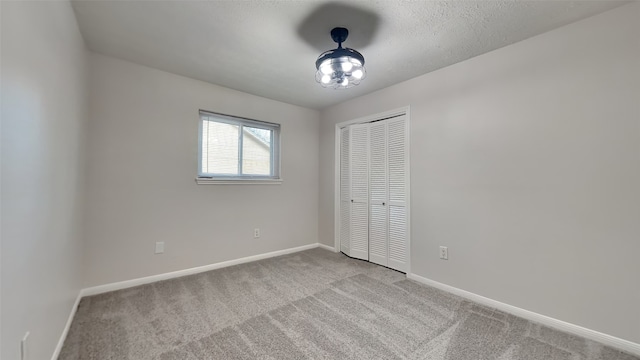 unfurnished bedroom featuring a closet, a textured ceiling, and light colored carpet