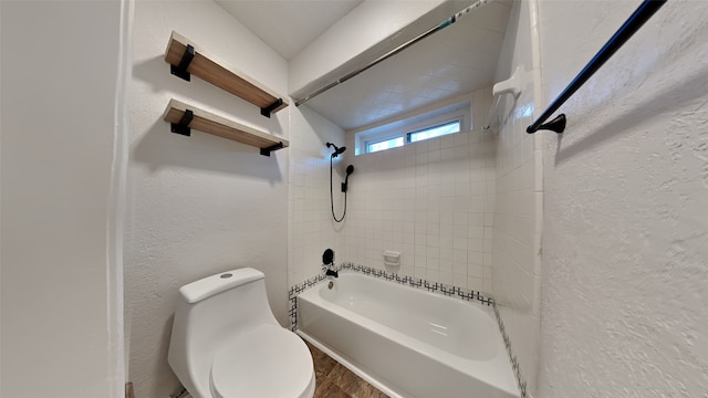 bathroom featuring toilet and tiled shower / bath