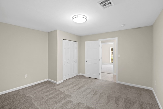 unfurnished bedroom with a closet and light colored carpet