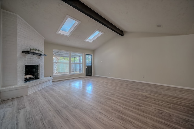 unfurnished living room featuring light hardwood / wood-style floors, a fireplace, and lofted ceiling with skylight