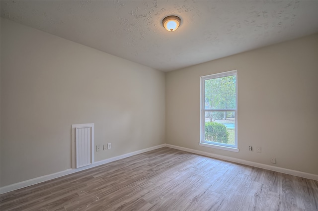 unfurnished room featuring a textured ceiling and light hardwood / wood-style flooring