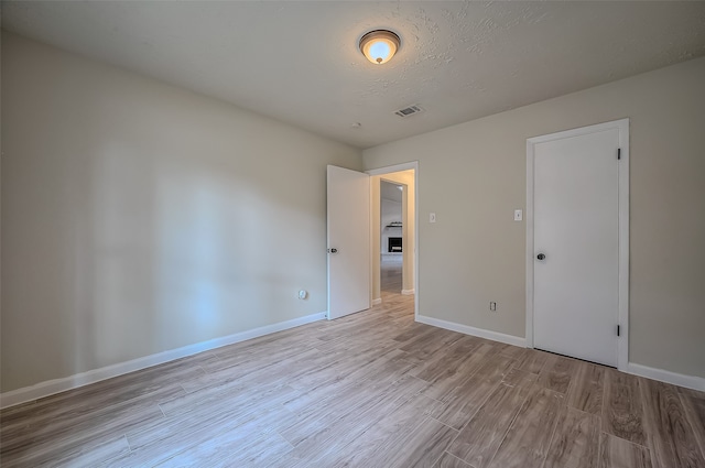 empty room featuring a textured ceiling and light wood-type flooring