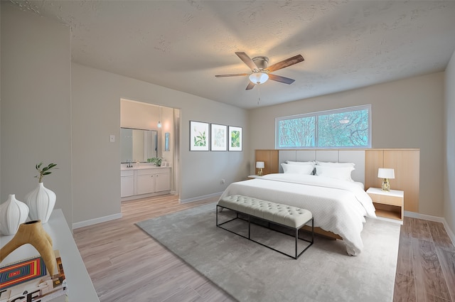 bedroom with ceiling fan, a textured ceiling, connected bathroom, light hardwood / wood-style floors, and sink