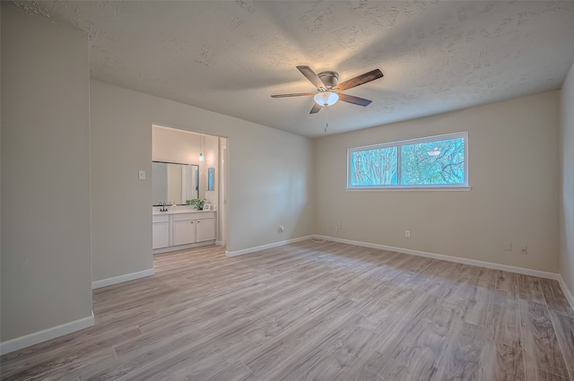 unfurnished bedroom featuring light hardwood / wood-style floors, a textured ceiling, ensuite bathroom, and ceiling fan