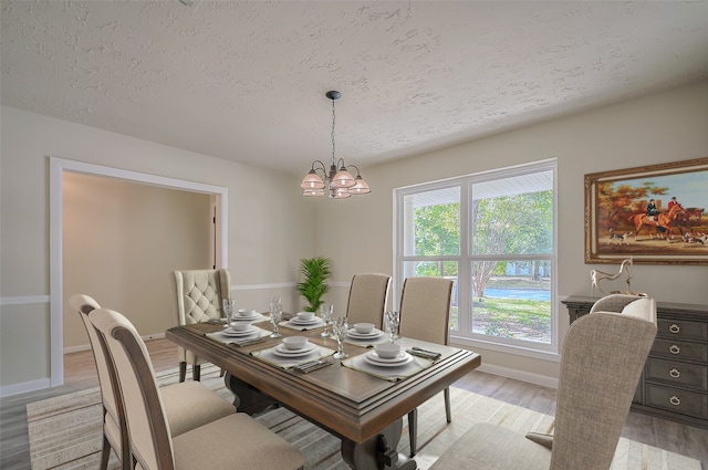 dining room featuring a textured ceiling, an inviting chandelier, and light wood-type flooring