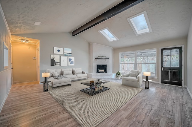 living room with lofted ceiling with skylight, a fireplace, and light hardwood / wood-style floors