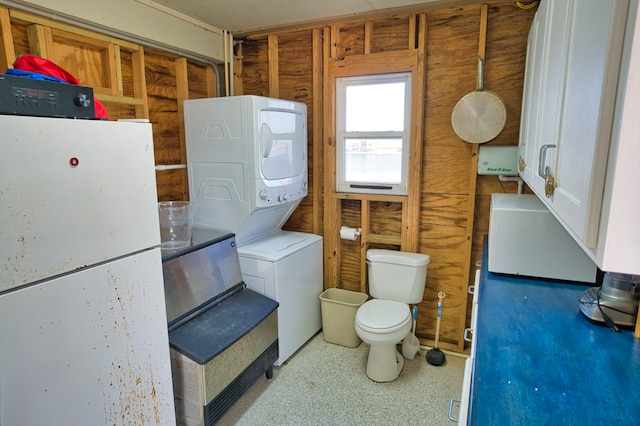 bathroom featuring toilet and stacked washer and dryer