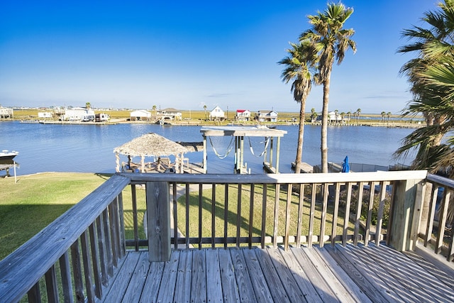 dock area with a yard and a deck with water view