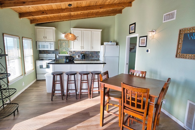 dining room with lofted ceiling with beams, wooden ceiling, and dark hardwood / wood-style floors