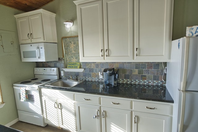 kitchen featuring dark stone counters, white cabinetry, decorative backsplash, a sink, and white appliances
