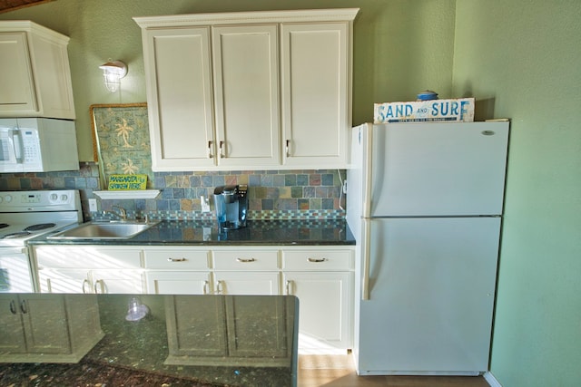 kitchen with white appliances, dark stone countertops, sink, and white cabinets