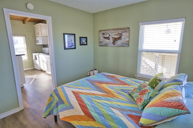 bedroom with wood finished floors, baseboards, and multiple windows