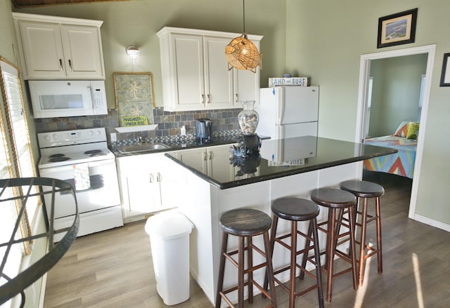 kitchen featuring tasteful backsplash, a kitchen island, light wood-style flooring, and white appliances